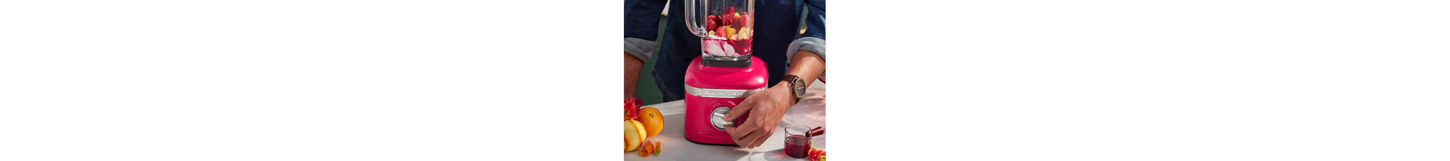 Person selecting settings on hibiscus KitchenAid® blender filled with fruit