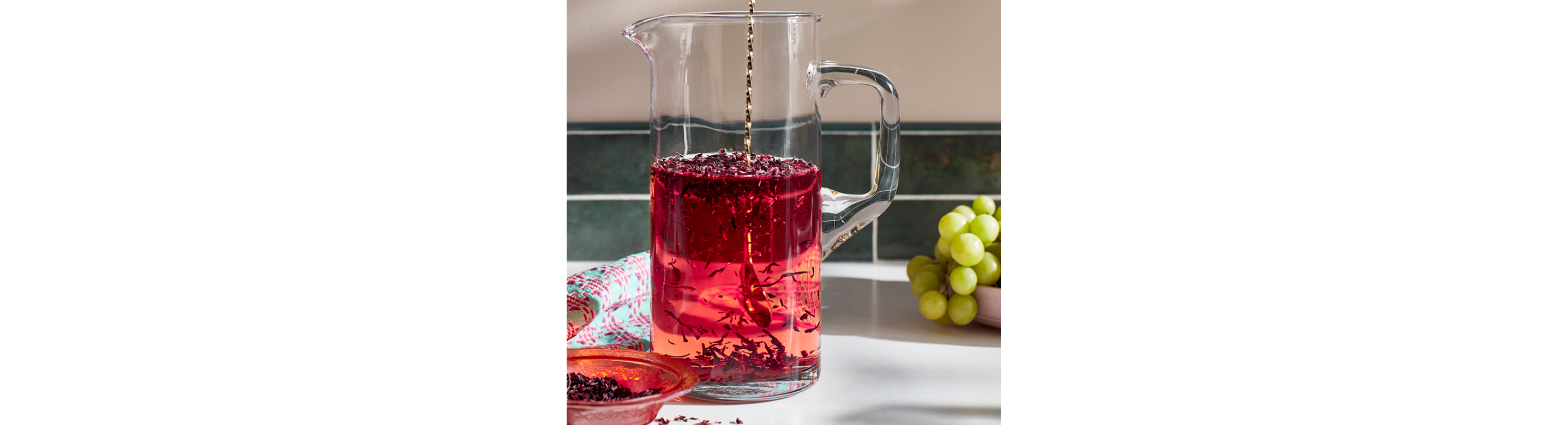 A cup of hibiscus tea, with hibiscus leaves scattered around the mug.