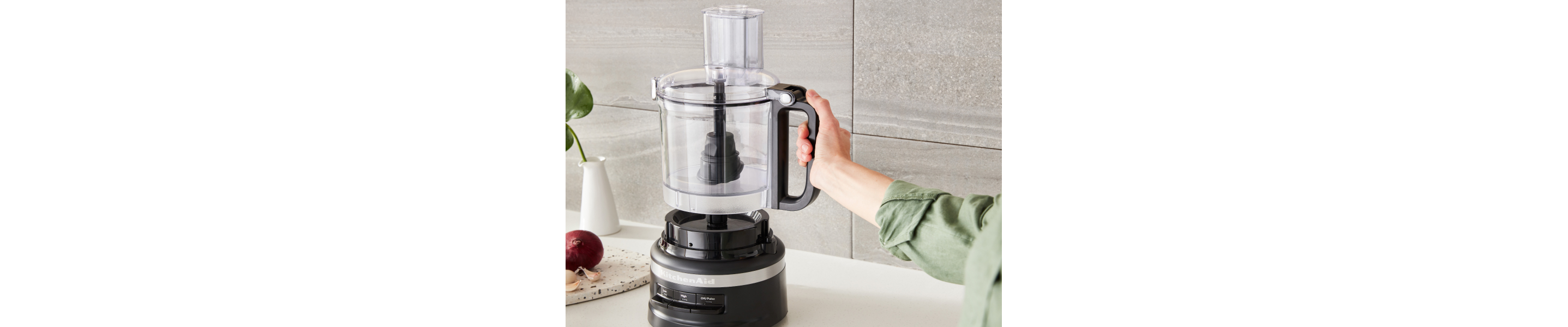 A woman attaching a KitchenAid® food processor bowl to the base of the appliance. 