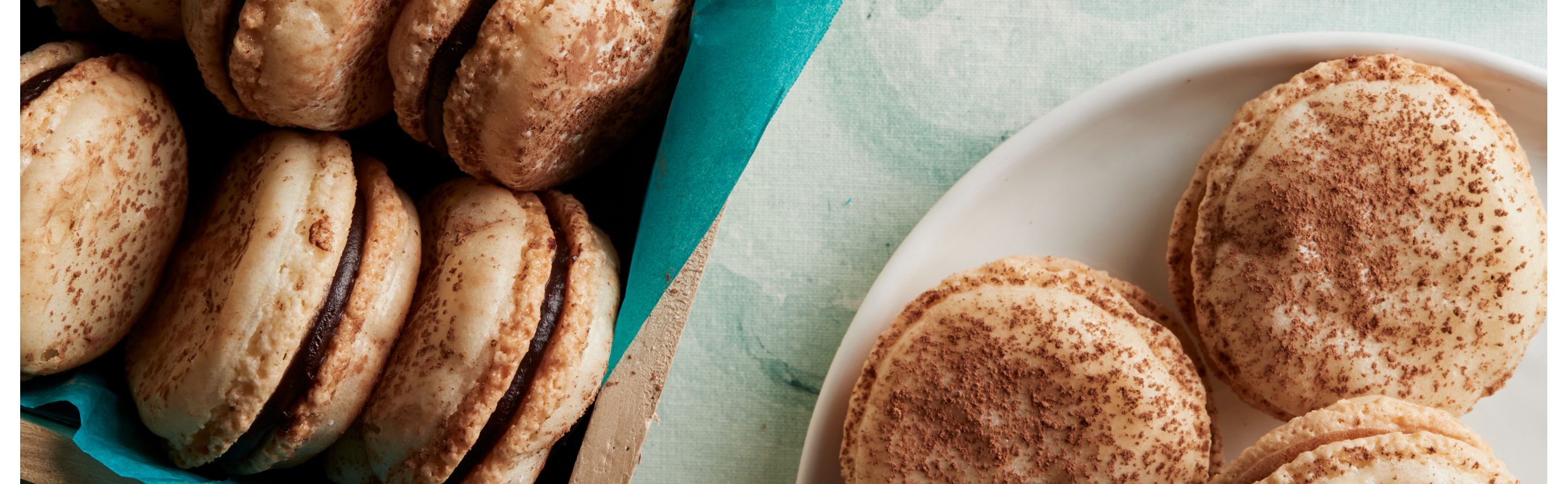 Almond macarons with dark chocolate ganache filling on a plate.