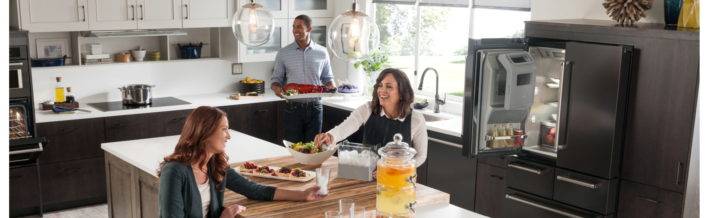 People gathered around a kitchen island with KitchenAid® appliances in the background