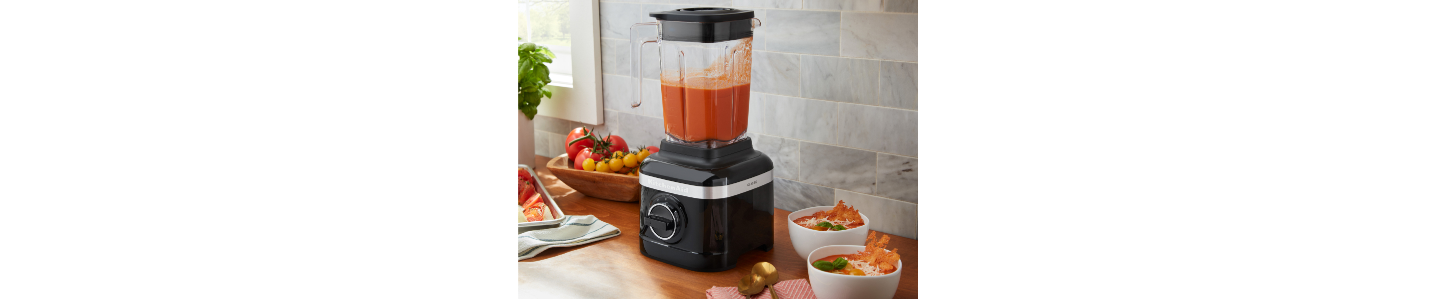 A KitchenAid® blender with freshly pureed soup ingredients on a modern kitchen counter.