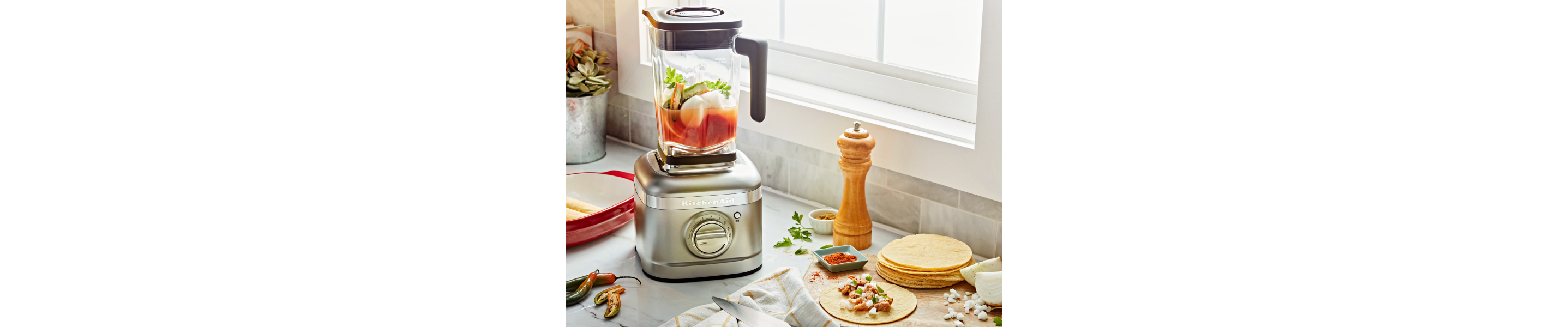 A KitchenAid® blender with chopped vegetables on a modern kitchen counter