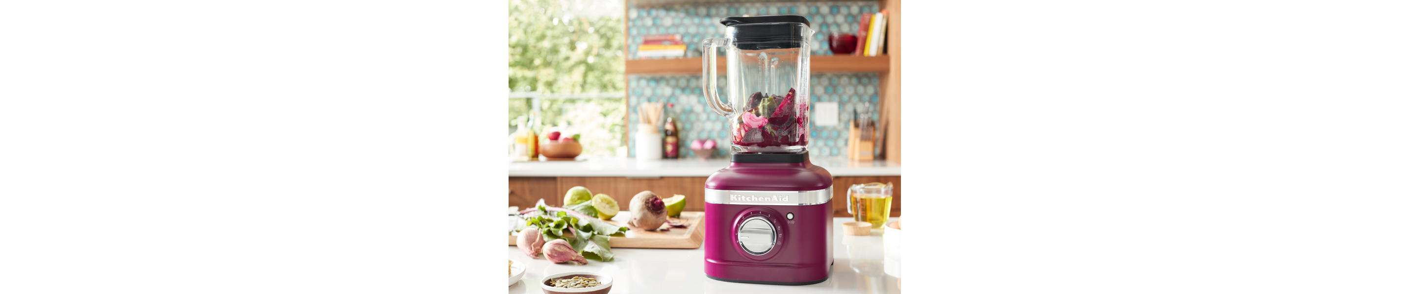 A KitchenAid® blender with fresh vegetables on a modern kitchen counter.