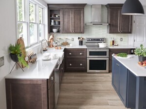 A bright kitchen with an island and white countertops, as well as a double oven range and a wall-mount canopy hood
