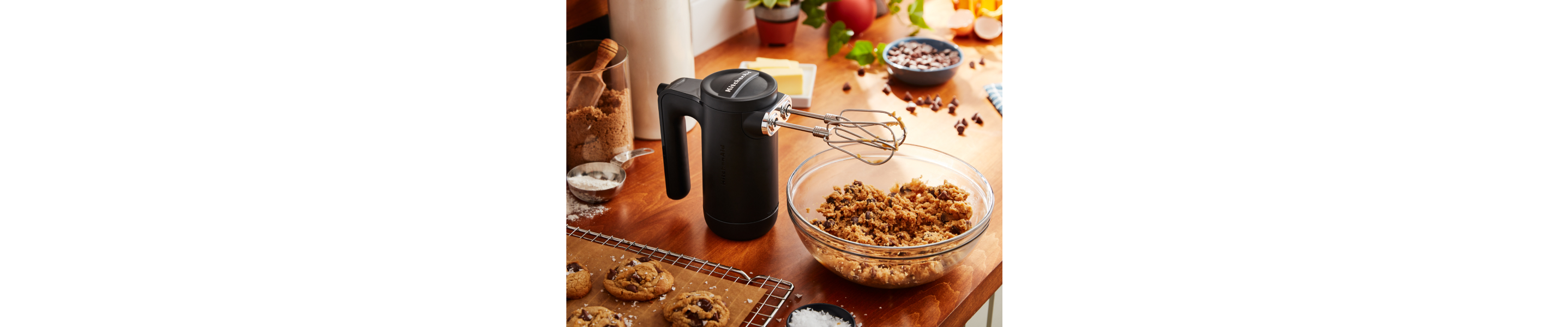A KitchenAid® cordless hand mixer and baking ingredients.
