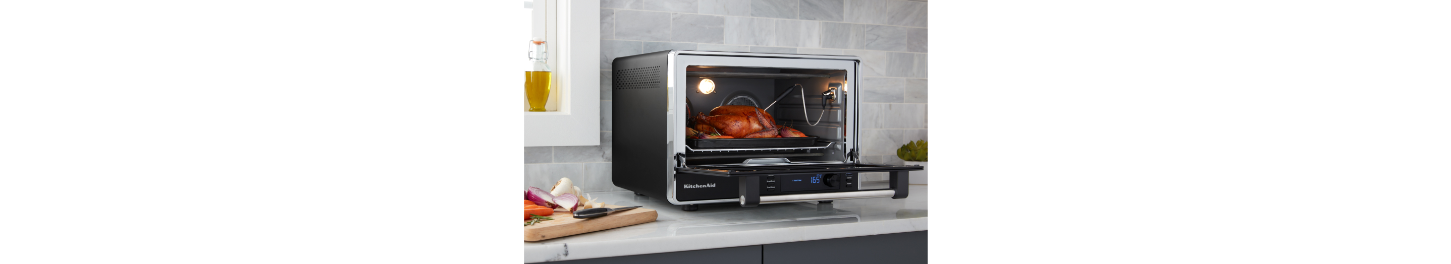 A KitchenAid® countertop oven with a roasted turkey inside.