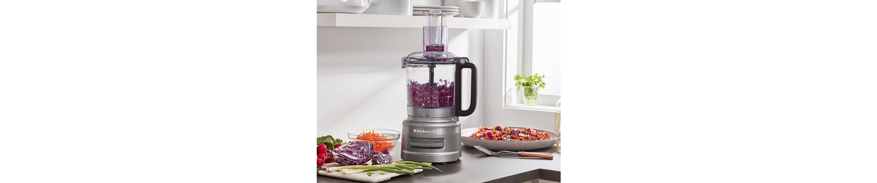 A KitchenAid® food processor with red onions inside.