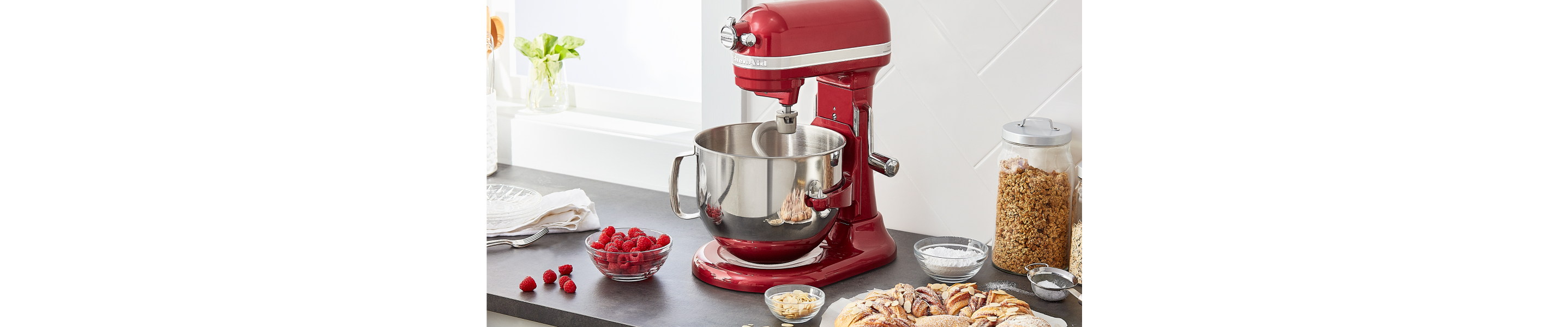 Berries, bread and jars of granola next to a KitchenAid® stand mixer.