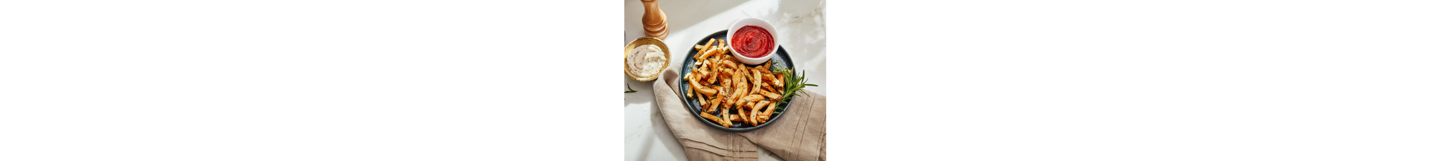 Herb garnished french fries on a plate with dip