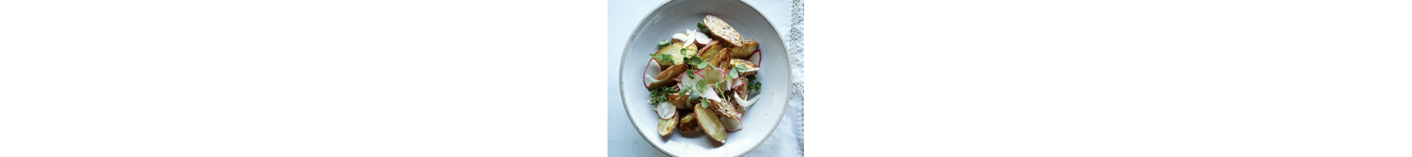 Roasted potatoes garnished with herbs in a bowl