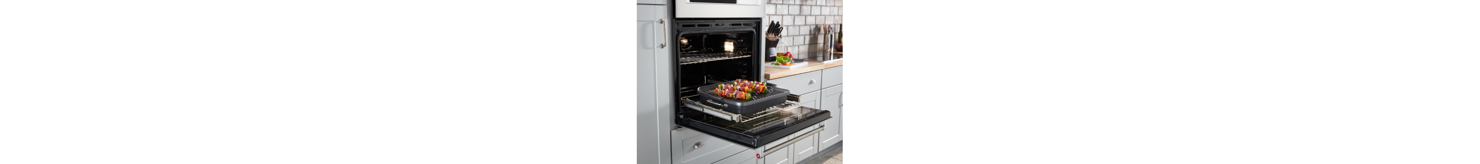 Vegetable kabobs on a grilling pan slid out on a gliding oven rack