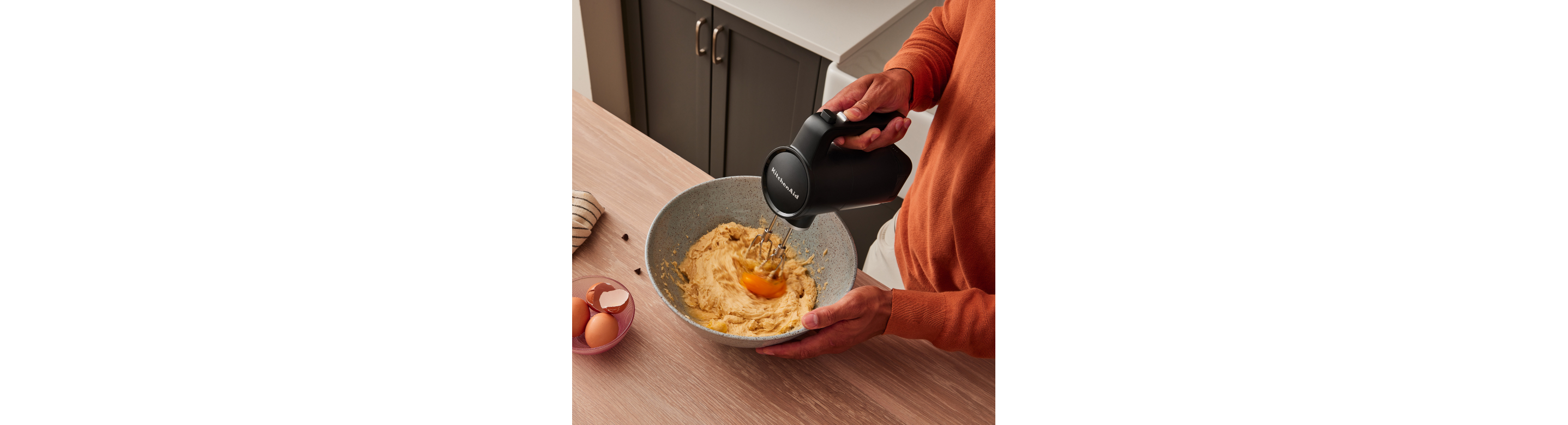 A person using a KitchenAid Go™ Hand Mixer to mix in eggs to batter.