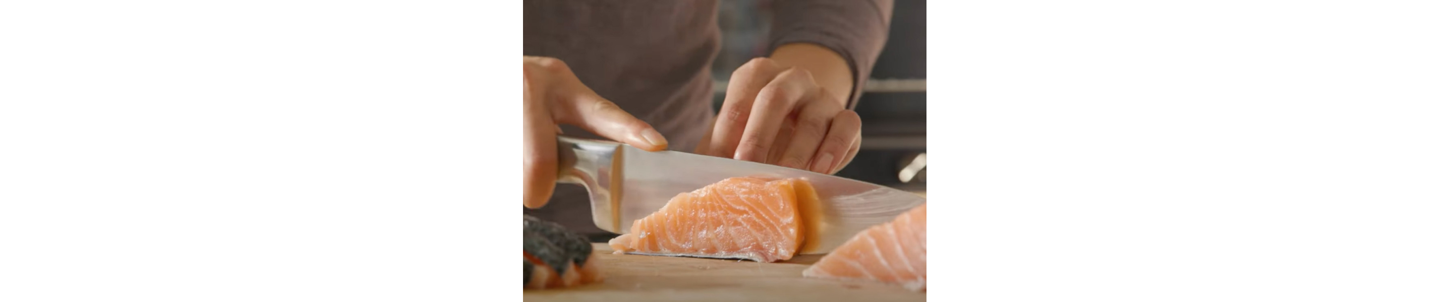  A man cutting fresh, raw salmon on a cutting board. 