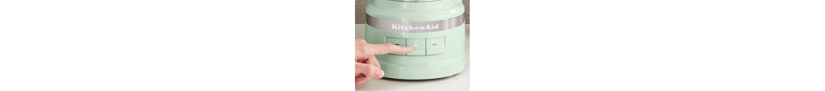 A person selecting a setting on a green KitchenAid® food processor