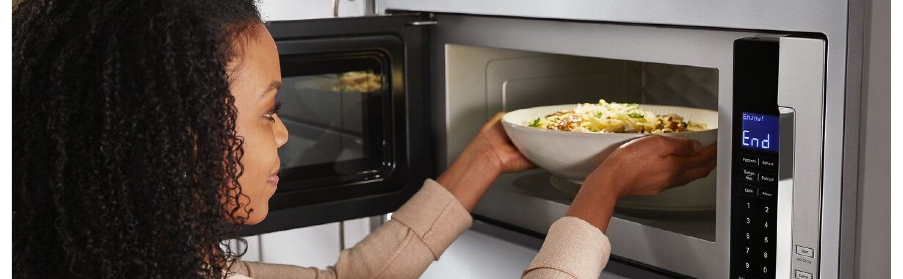 Person placing a bowl inside a built-in microwave