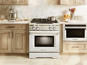 A KitchenAid® Microwave, installed at waist height, to the right of a range and surrounded by cabinetry