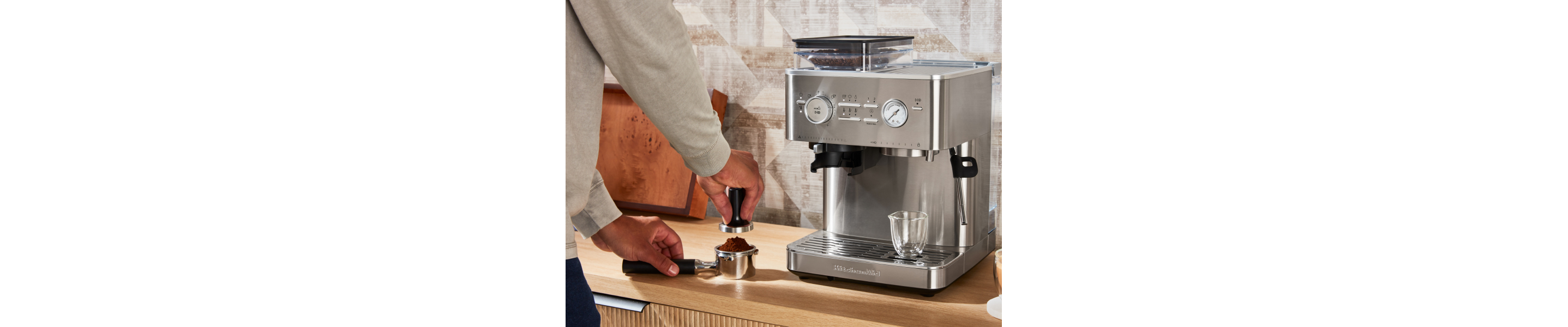Person tamping espresso next to a KitchenAid® Semi Automatic Espresso Machine