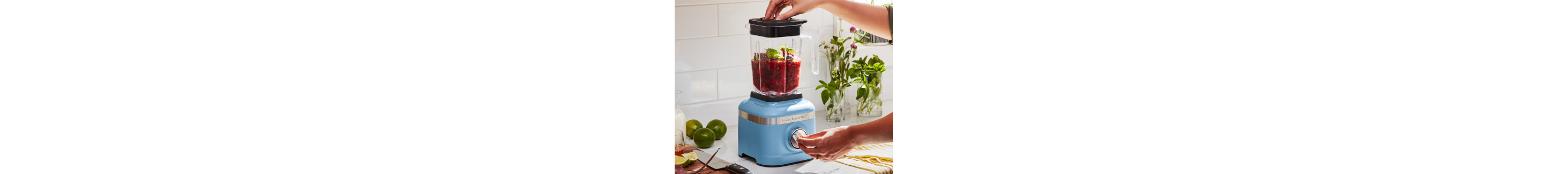 A person using a blue KitchenAid® blender.