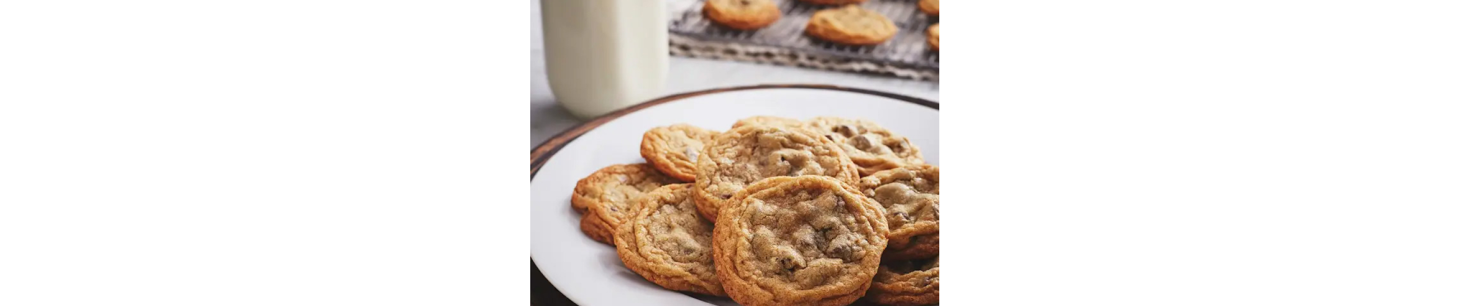 Baked chocolate chip cookies on a plate next to a cooling rack