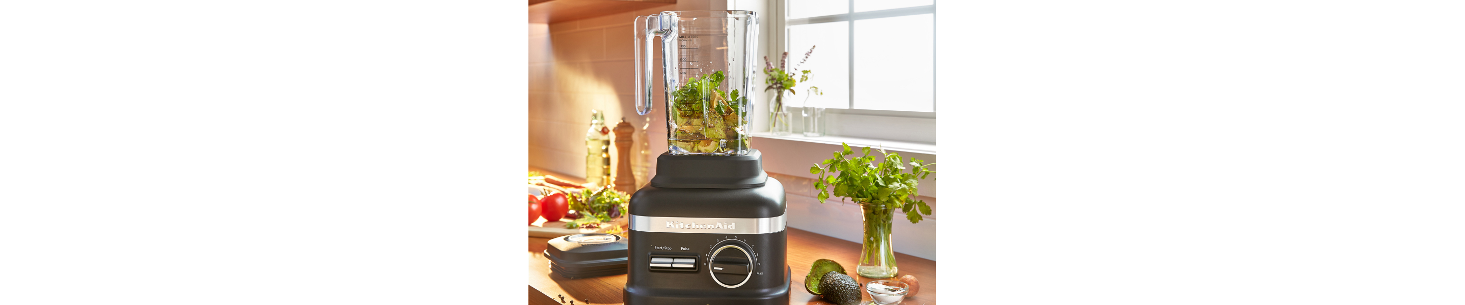 Pesto ingredients inside a black KitchenAid® blender