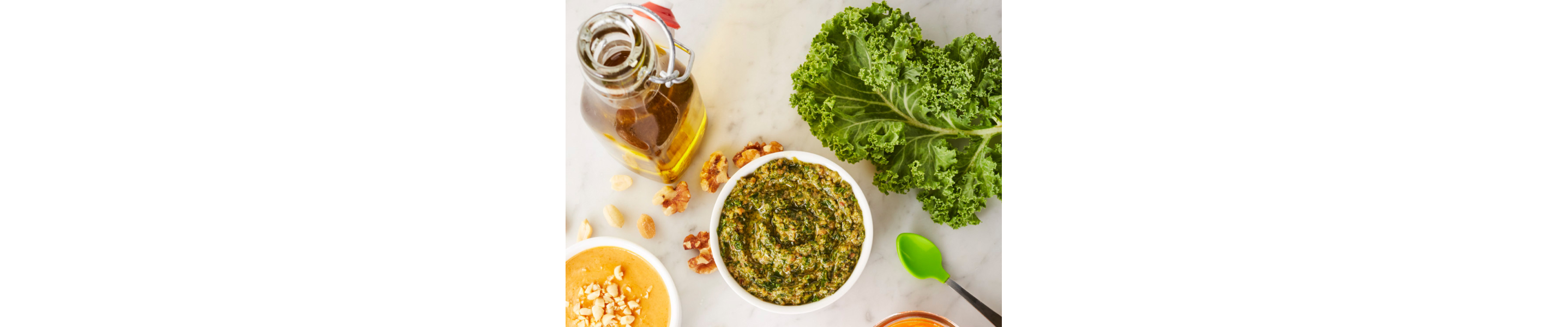 Homemade pesto next to a bottle of oil and kale