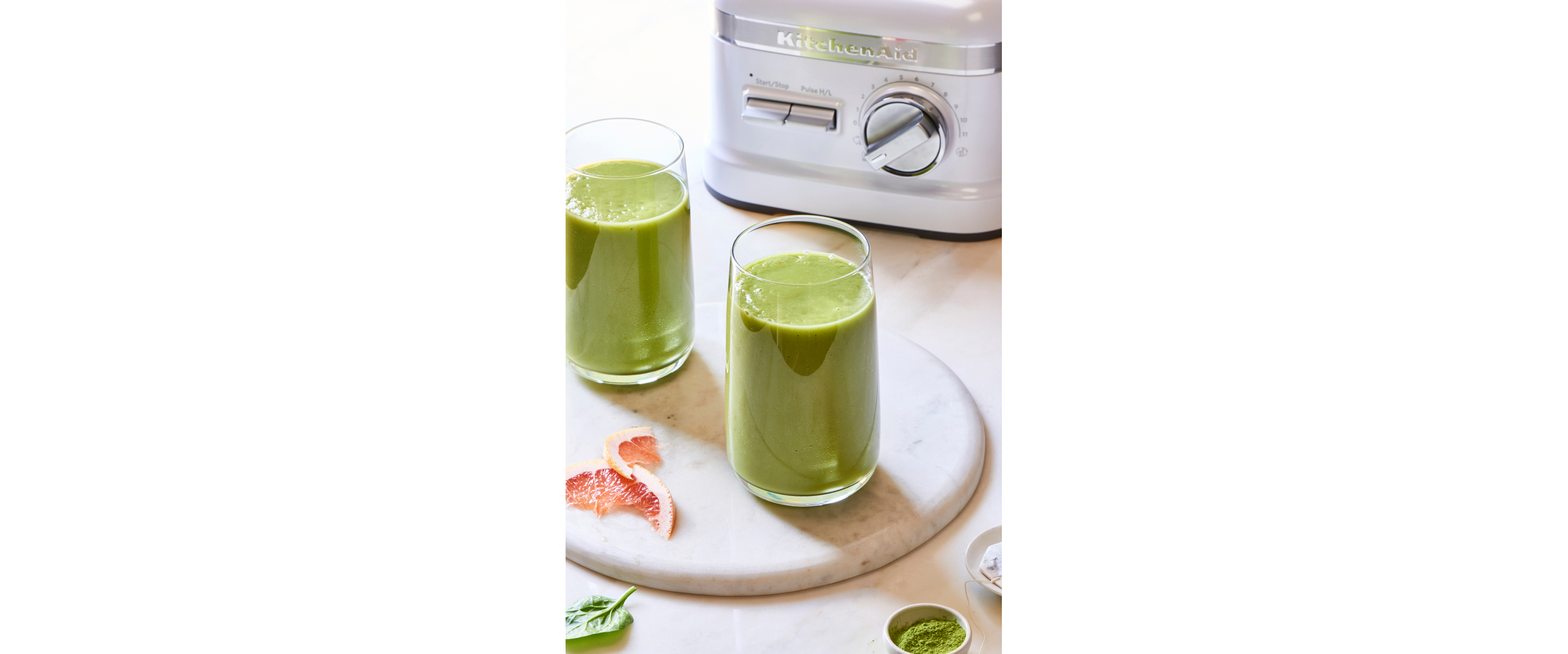 Green juice in glasses next to KitchenAid® blender