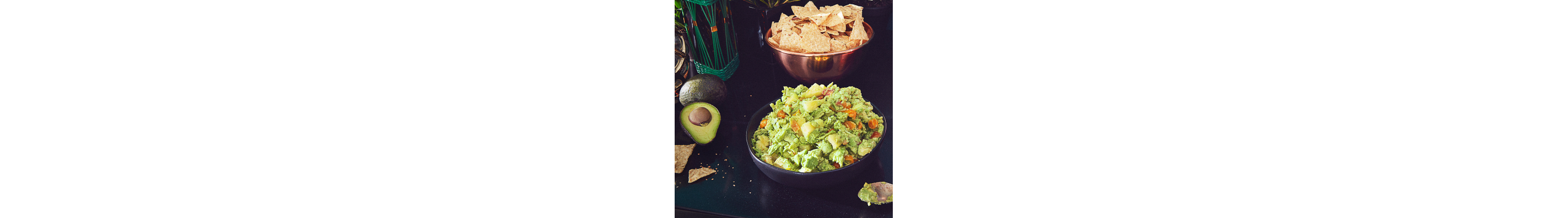 A bowl of fresh guacamole next to a bowl of tortilla chips.