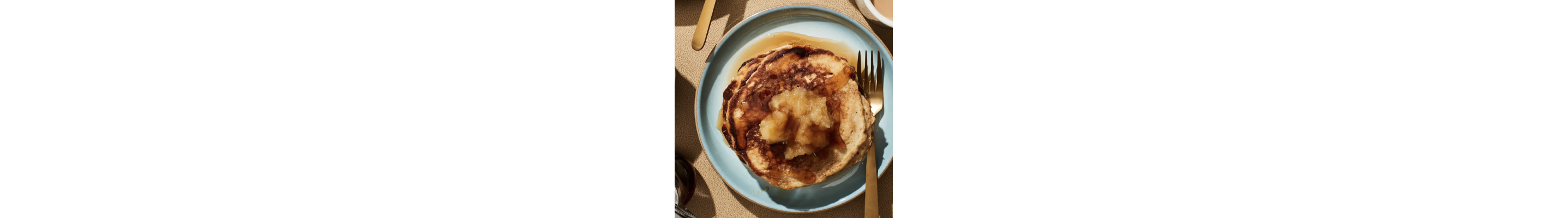 Birds-eye view of homemade pancakes topped with syrup and homemade applesauce