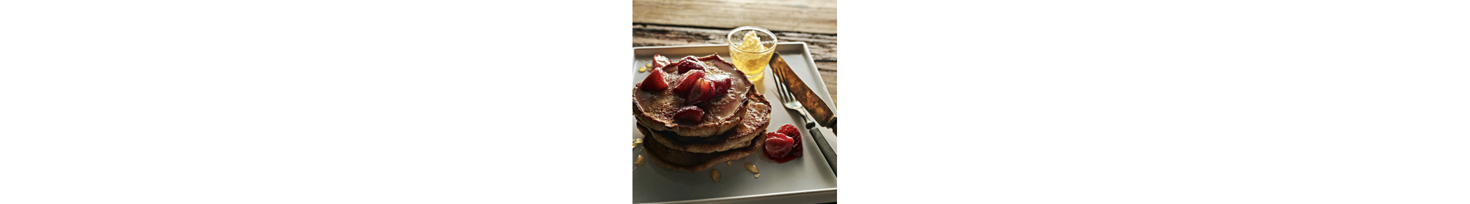Homemade pancakes on tray topped with fresh strawberries