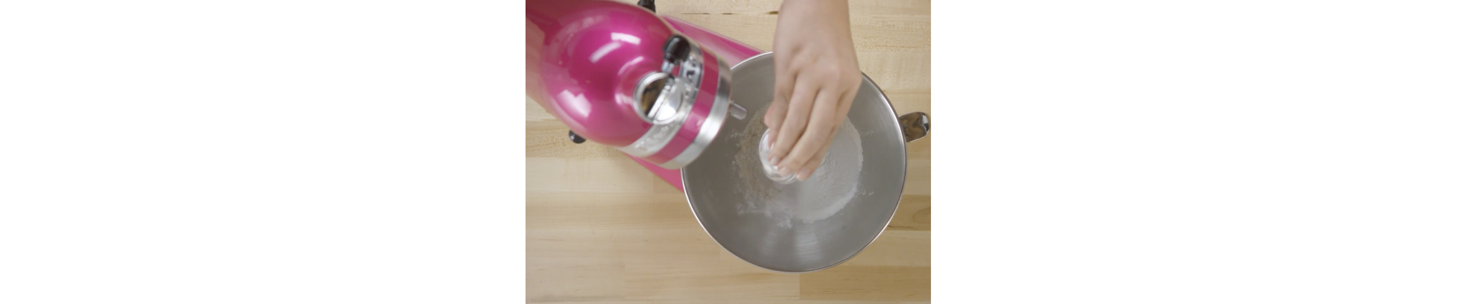 Close-up of person adding ingredients to stand mixer bowl