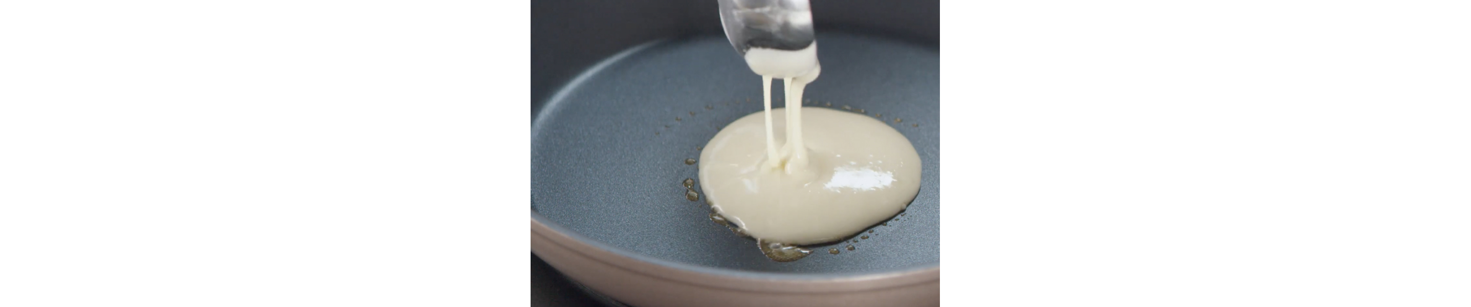 Person pouring pancake batter into prepared skillet