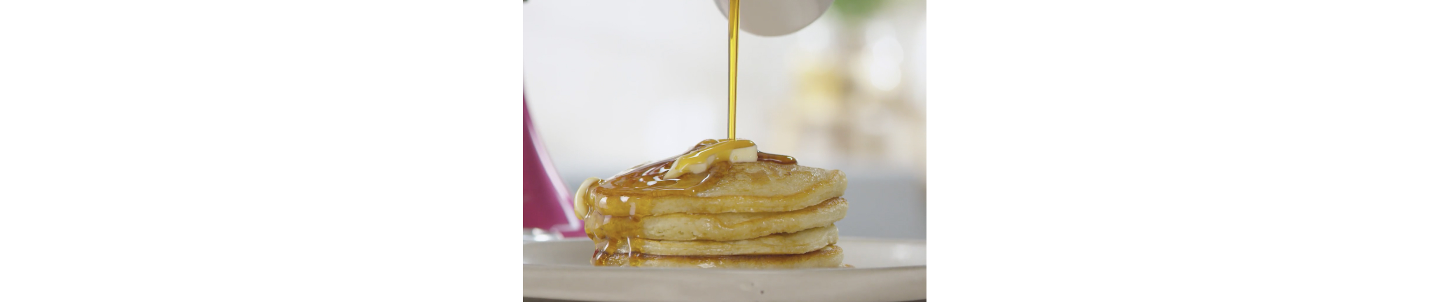Syrup pouring over prepared stack of pancakes