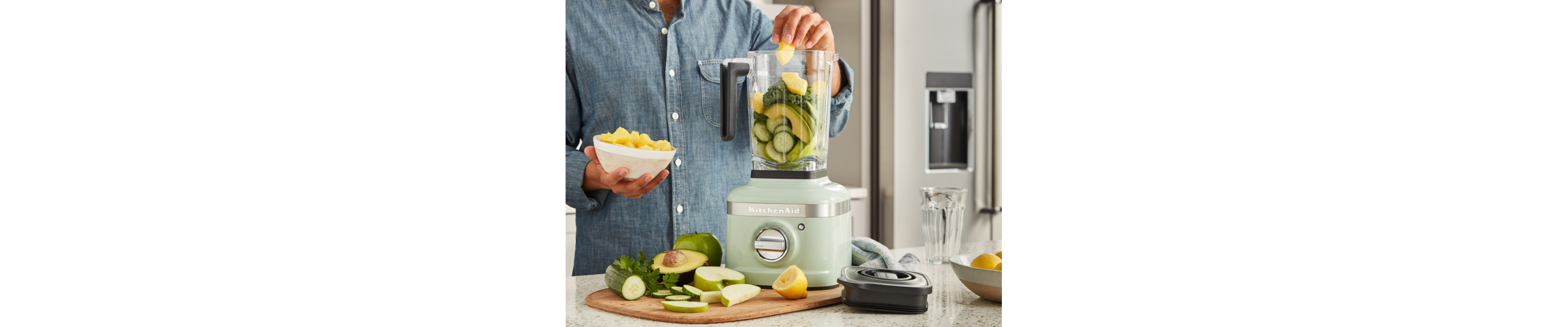 Person adding fruits and vegetables to a blender jar