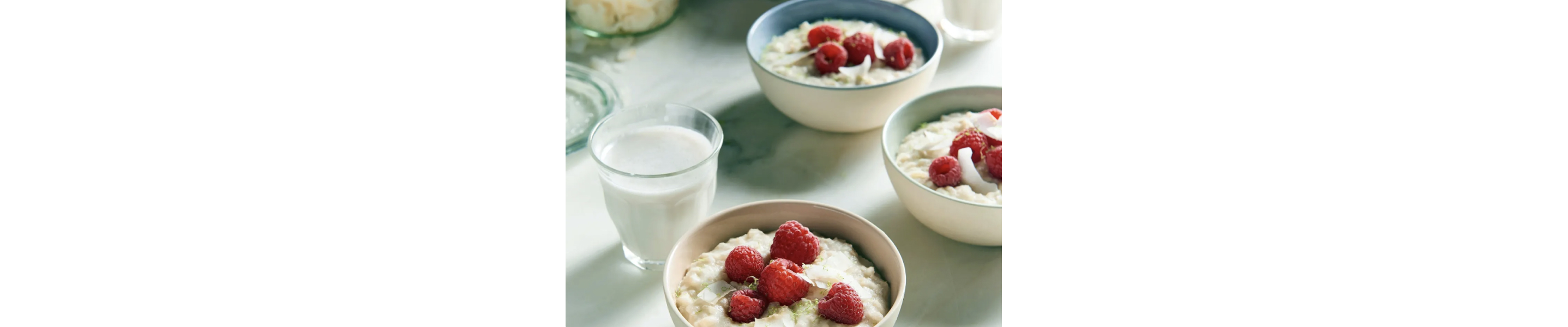 Bowls of lime coconut rice porridge with raspberries.
