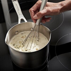 A hand whisking rice and heavy cream