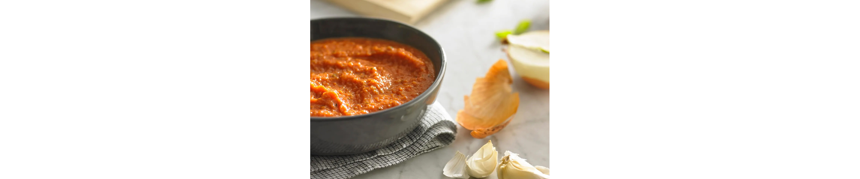 Bowl of marinara next to cloves of garlic