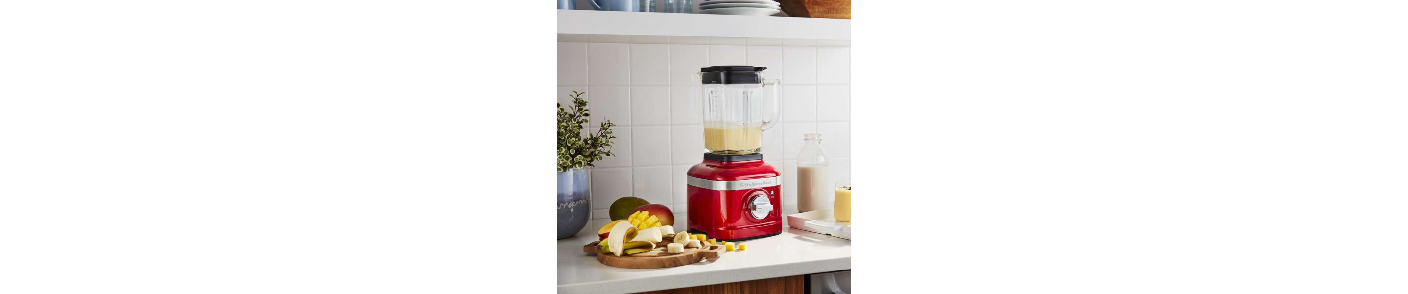 Red KitchenAid® blender next to sliced bananas on a cutting board