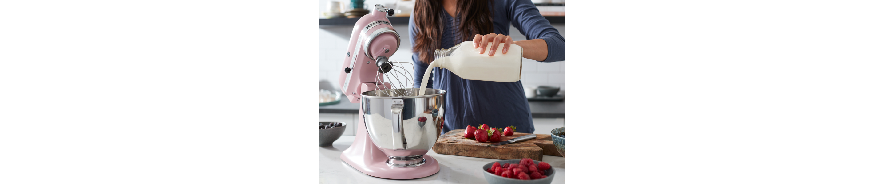 Woman pouring heavy cream into a pink KitchenAid® stand mixer 