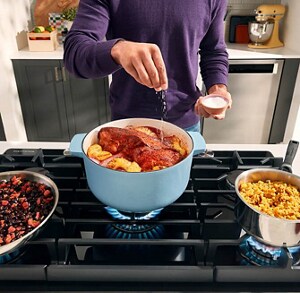 A person preparing three dishes on a gas stove