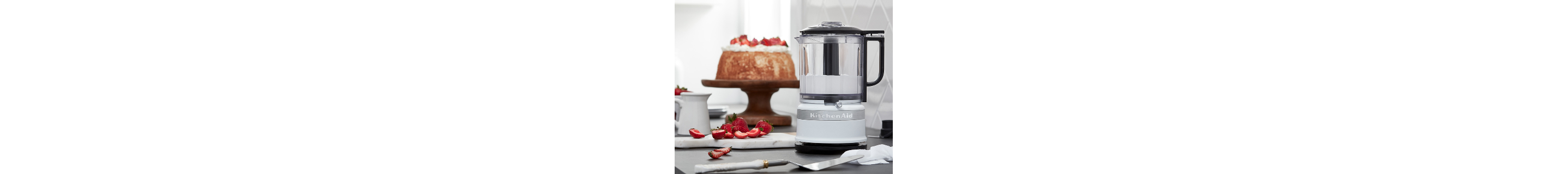 Silver food chopper filled with whipped topping next to cake on counter