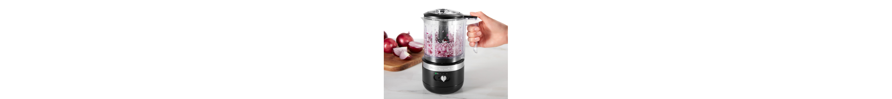 Person holding black food chopper with minced purple onion inside