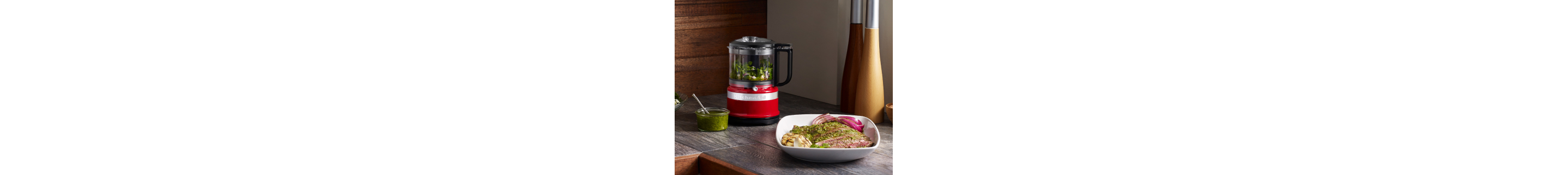Red food chopper on counter filled with ingredients