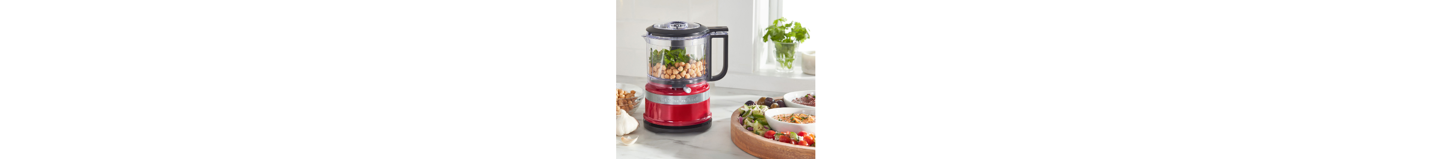 Red food chopper on counter filled with chickpeas and herbs