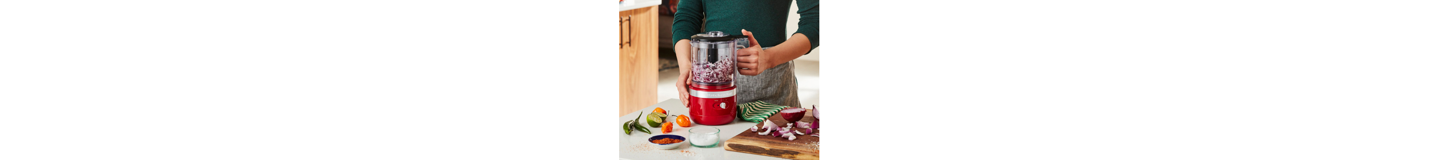 Person pulsing red onions in red food chopper on counter with ingredients