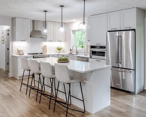A bright white kitchen island with stool seating and pendant lights overhead