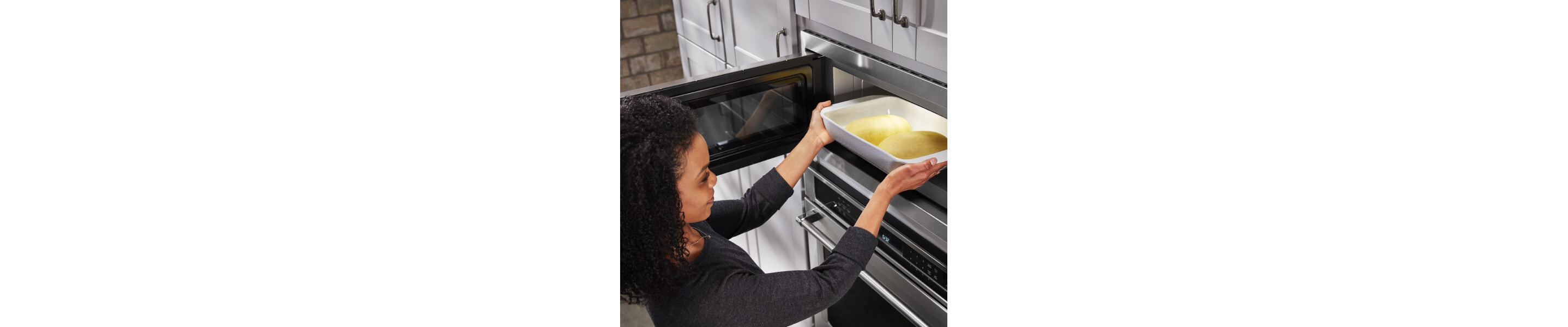 Person putting a 9-inch by 13-inch pan with bread dough in the microwave