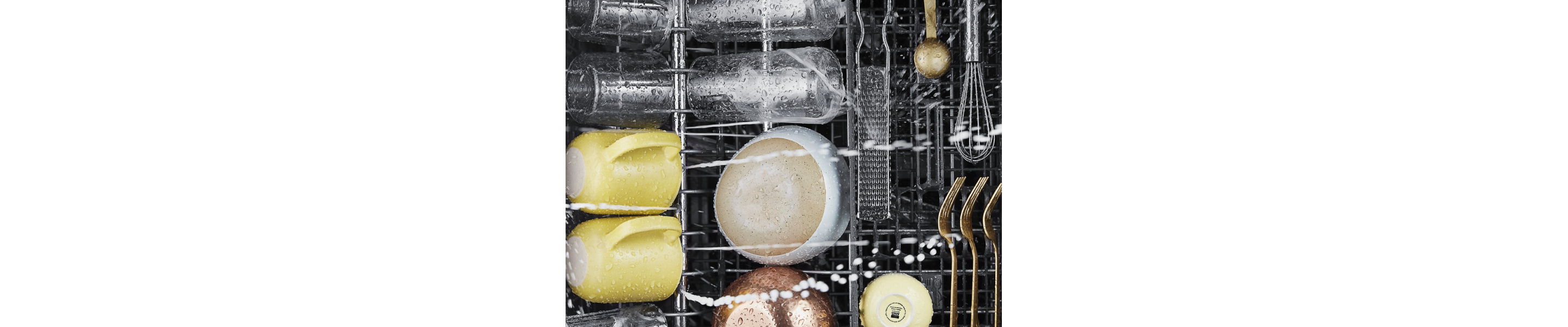 Cups, bowls and utensils being washed in a dishwasher
