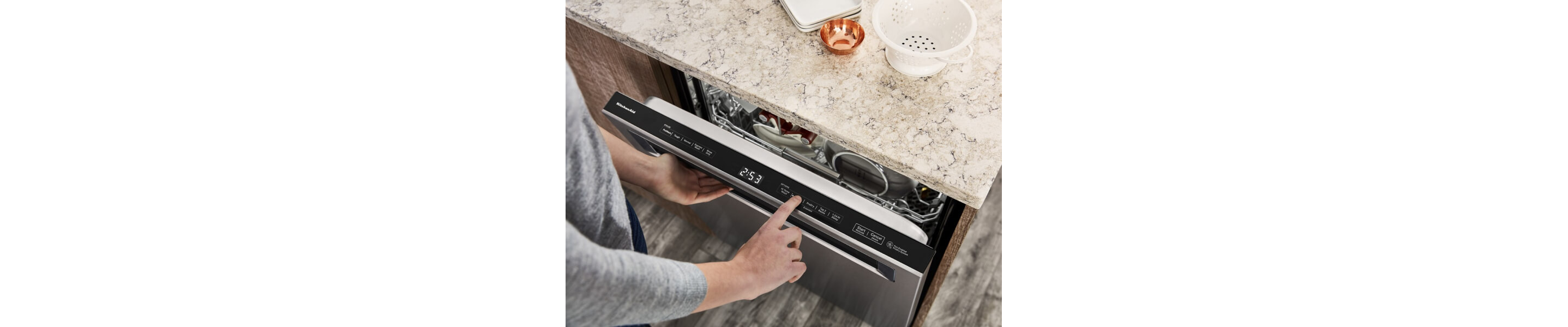 A hand selecting settings on a KitchenAid® dishwasher