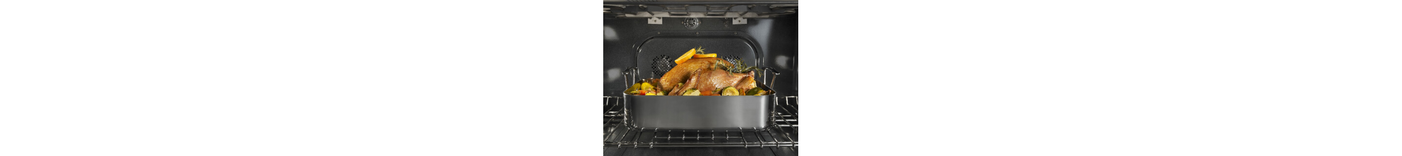 A turkey in a roasting pan on the top rack inside an oven range
